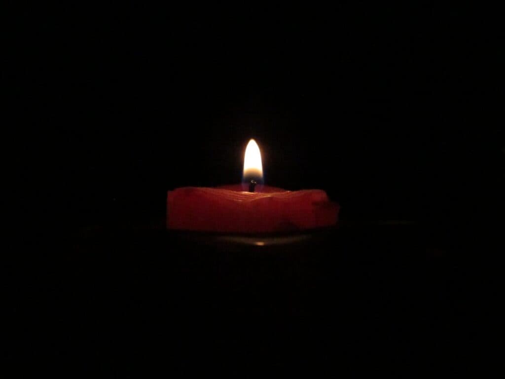 red lighted candle on dark room