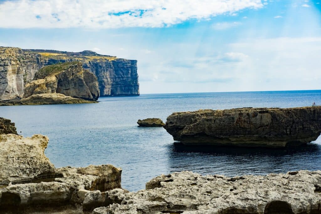 cliff beside sea water under bright sky