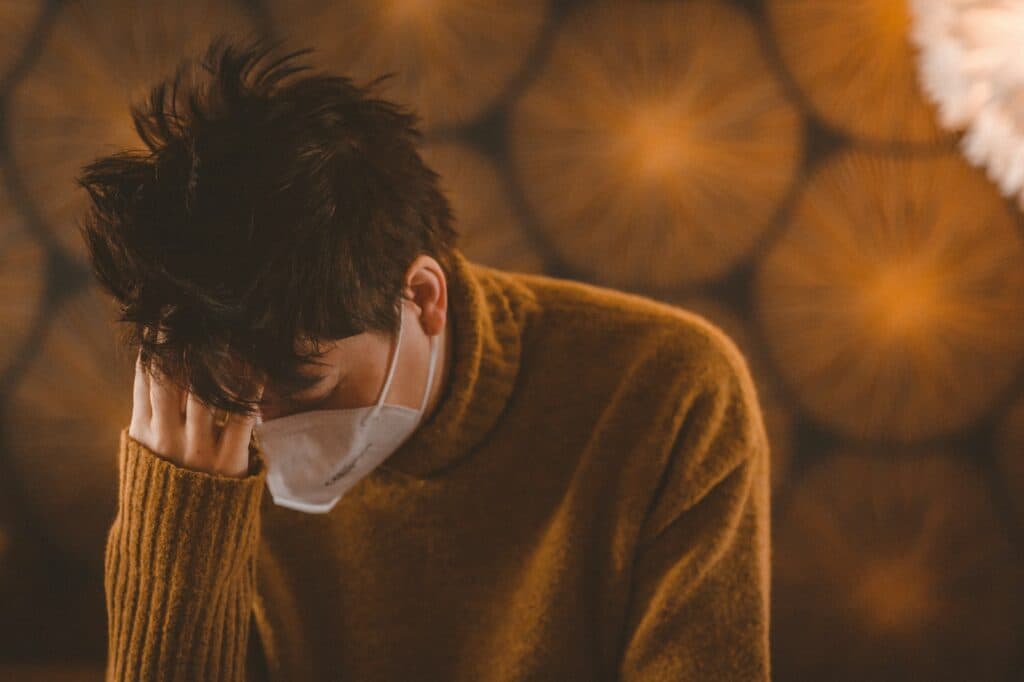 man in brown coat wearing white face mask