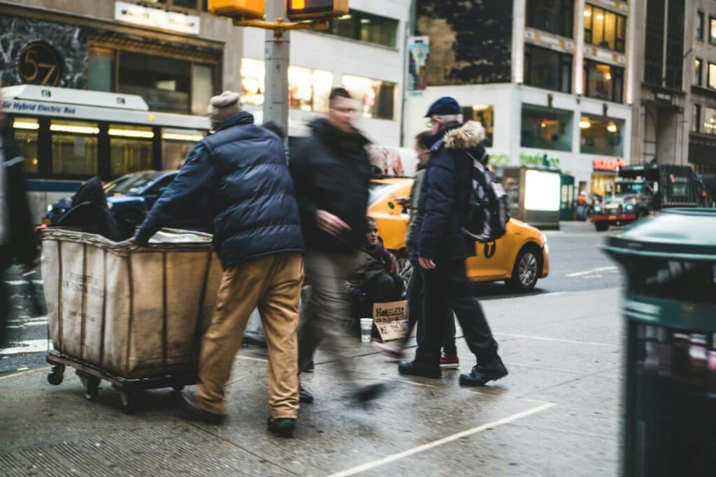 man walking on street beside man pushing cart