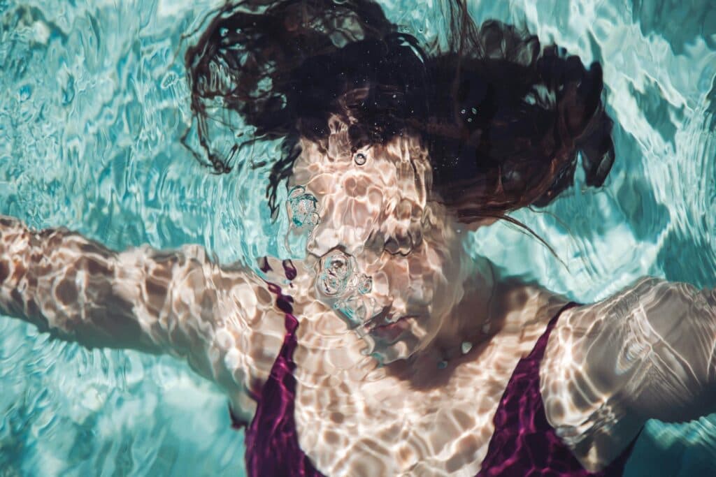 A woman swims underwater with bubbles.