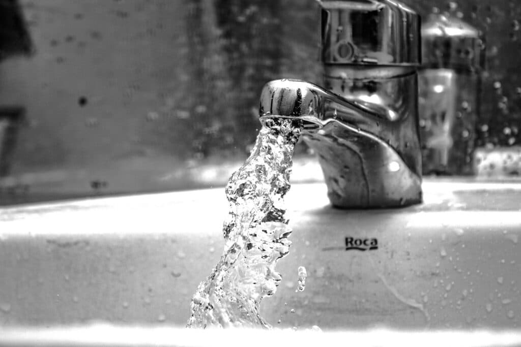 water falling from faucet in grayscale photography