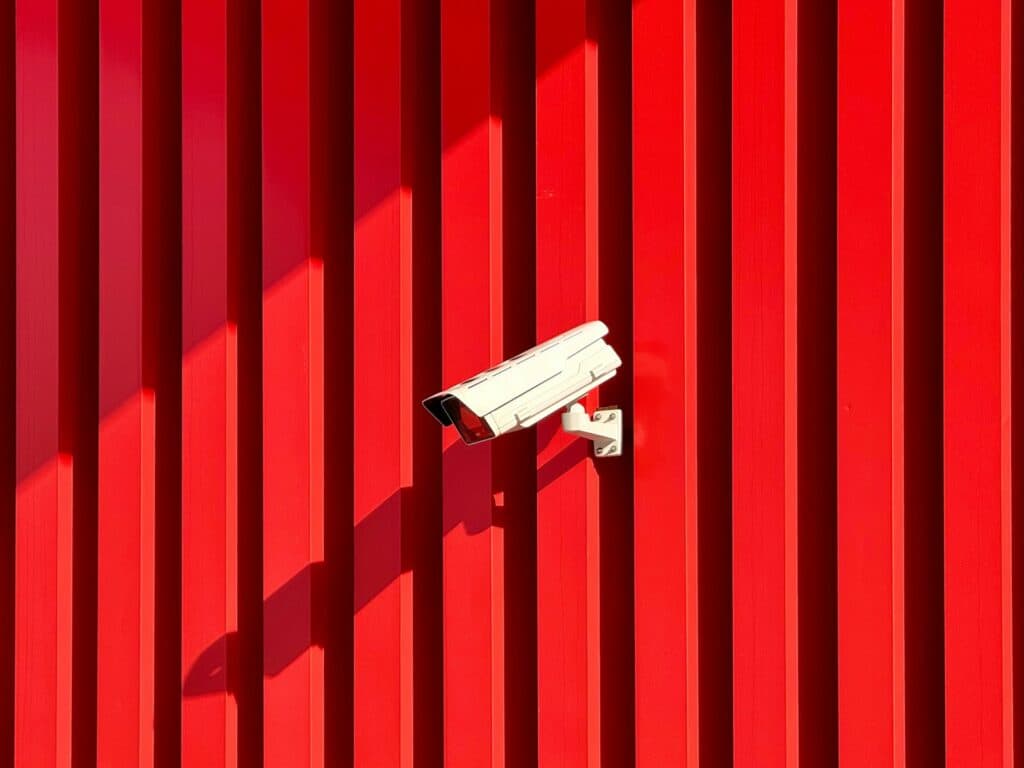 Cctv camera is mounted on a red wall.