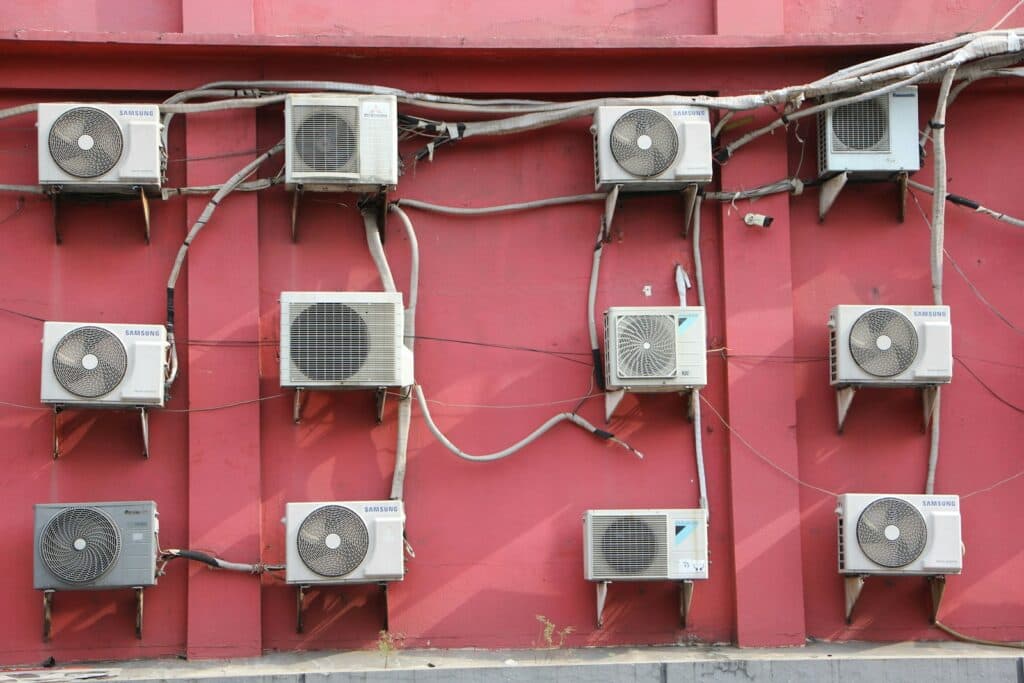 A bunch of air conditioners on a red wall