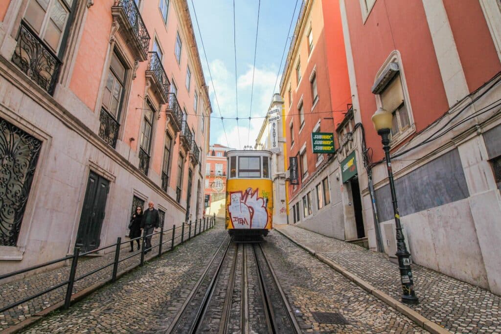 Yellow tram ascends a steep cobblestone street.