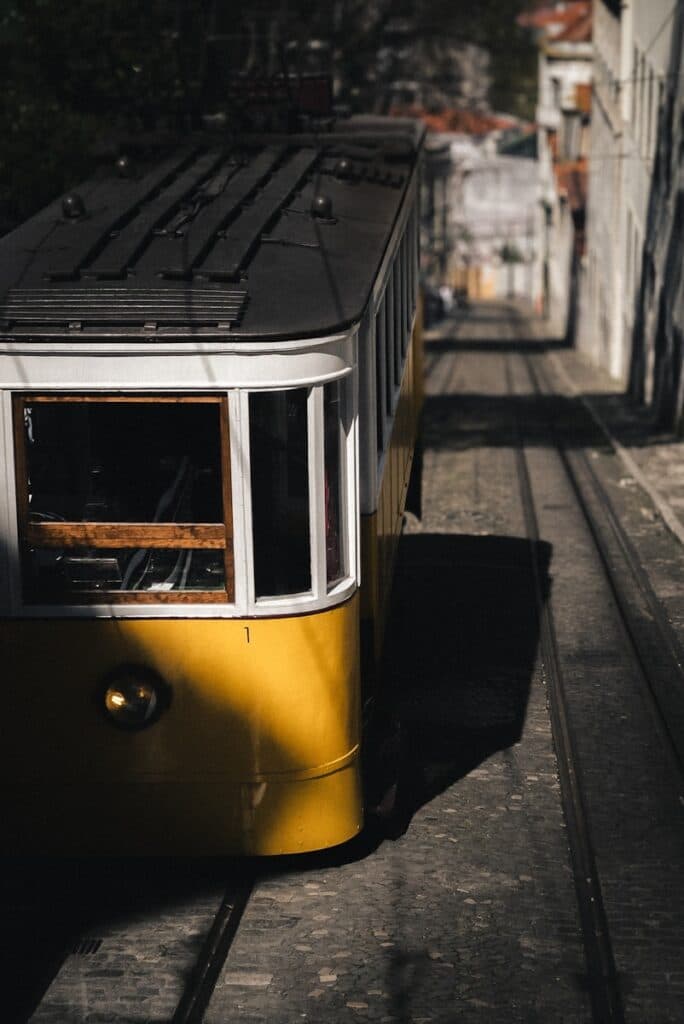 A yellow tram travels uphill on its tracks.