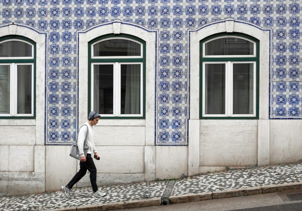 A man walking down a street past a building