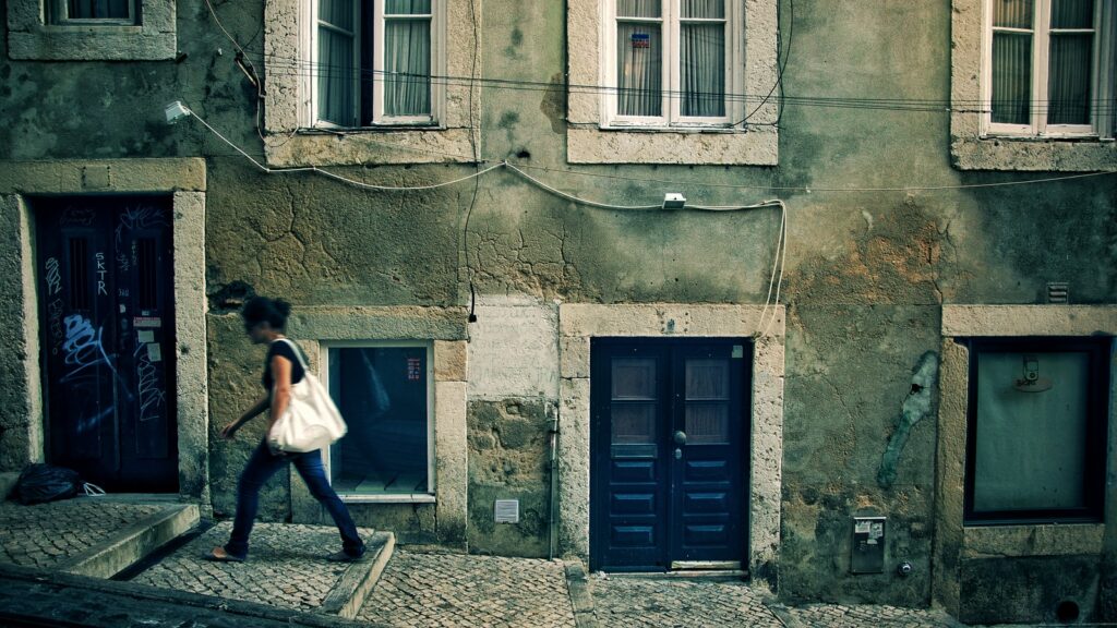 woman walking near concrete house at daytime