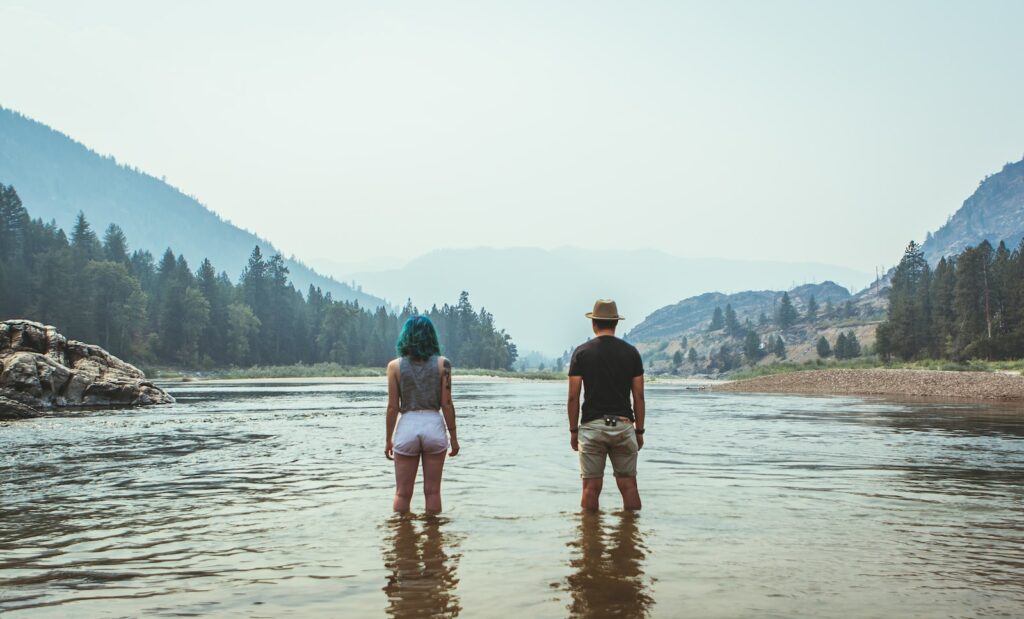 man and woman standing on river