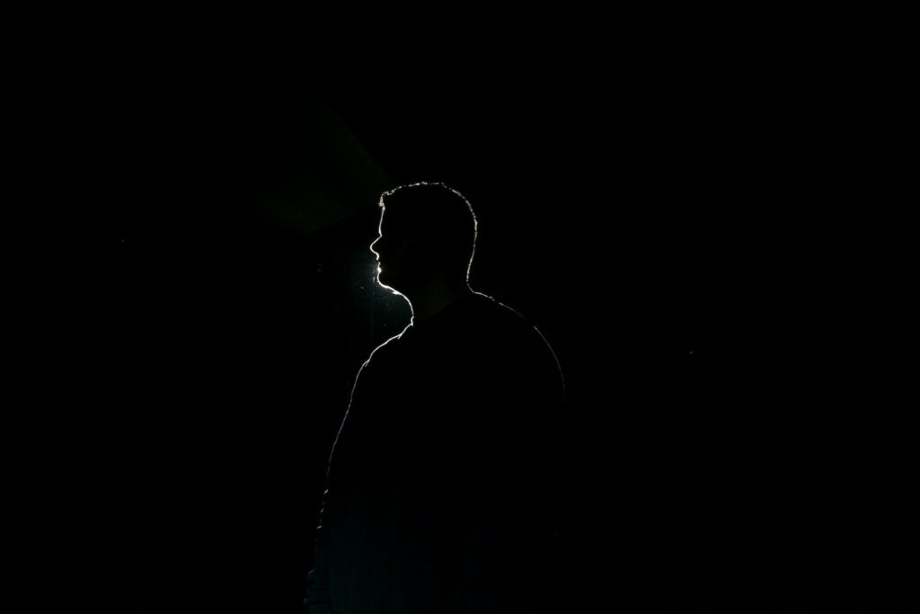 silhouette of man standing in dark room