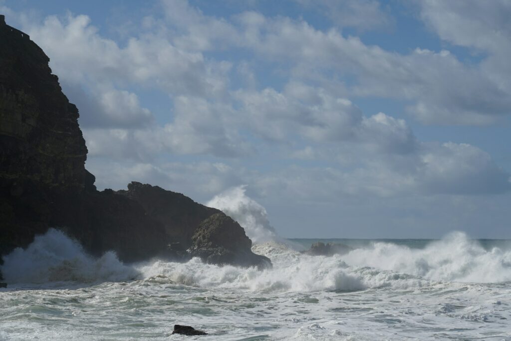 a large wave crashes against a rocky cliff